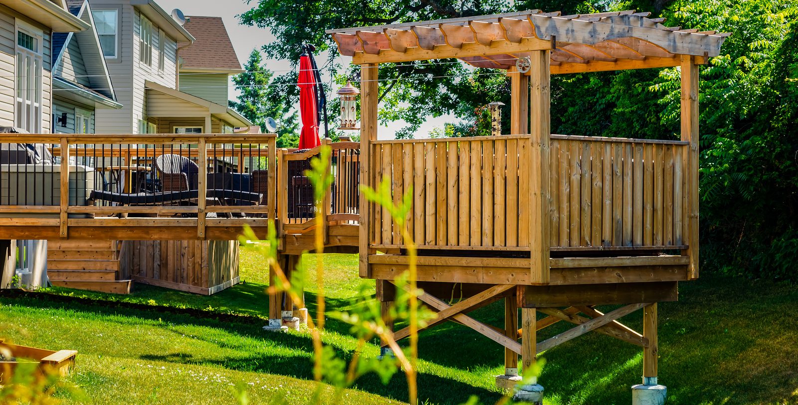 Raised backyard deck with built-in pergola seating area, pressure-treated framing, code-compliant railings