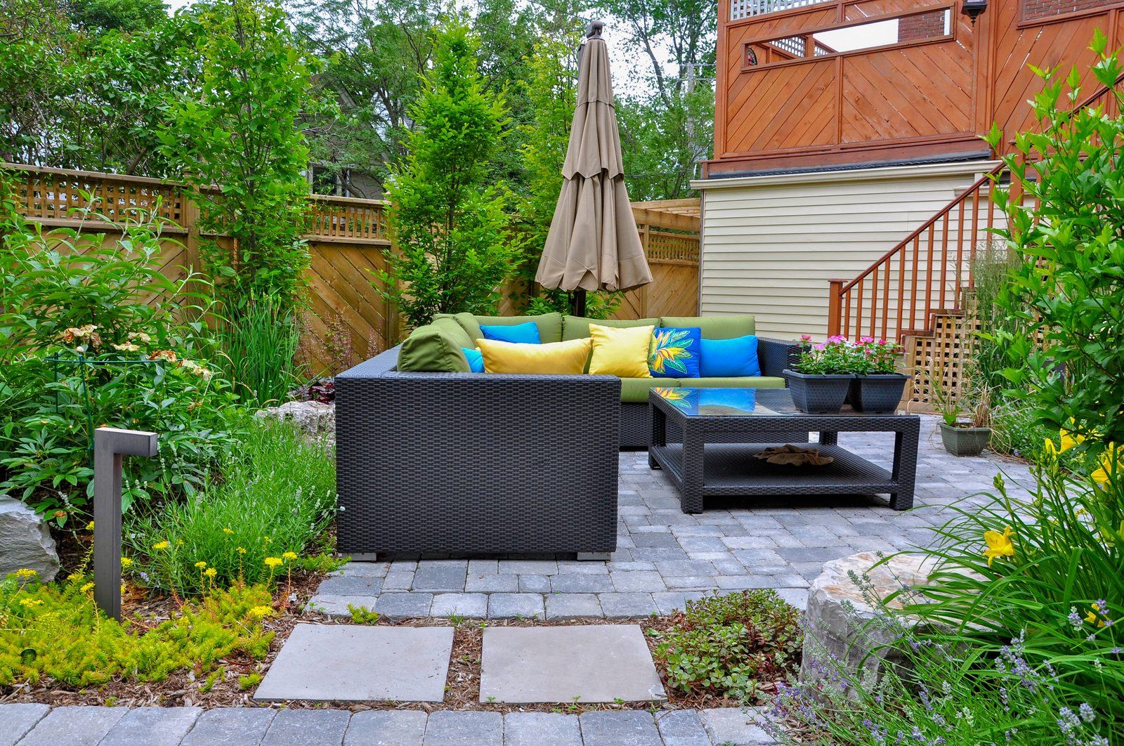 Paver patio with sectional outdoor seating, flagstone path and lush garden surround